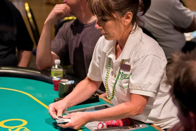 Una croupier distribuisce le carte al tavolo verde