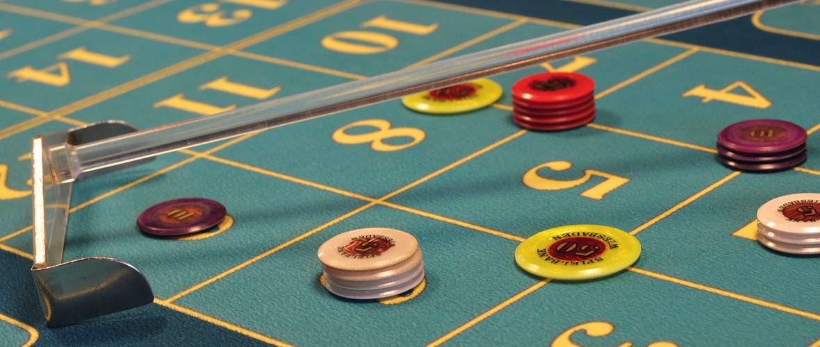 Fiche impilate sul tappeto verde di un tavolo da roulette, accanto al rastrello